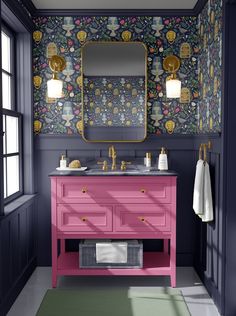 a bathroom with a pink vanity and floral wallpaper on the walls, along with a gold framed mirror