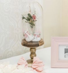 a baby's shoes are under a glass clochet with flowers in it