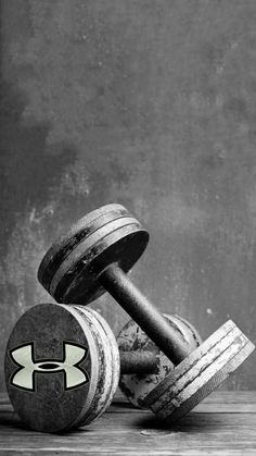 two dumbbells sitting on top of each other in front of a concrete wall