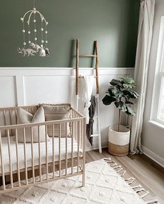 a baby's room with a crib, rug and potted plant in the corner