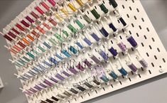 an array of different colored spools of thread hanging on a wall in front of a sign