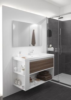 a bathroom with a walk in shower next to a white sink and brown towel on the shelf