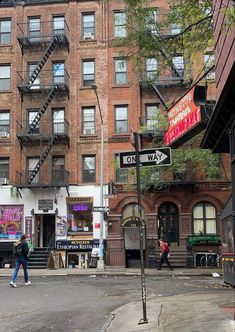 people are walking down the street in front of some tall buildings with fire escapes on them