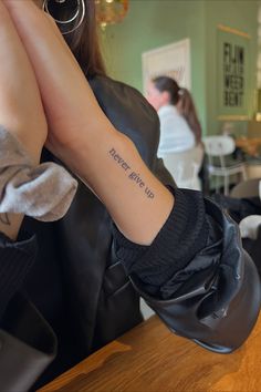 a woman with a tattoo on her arm sitting at a table