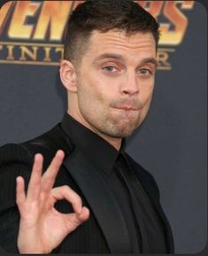 a man in a black suit making the vulcan sign with his hand at an event