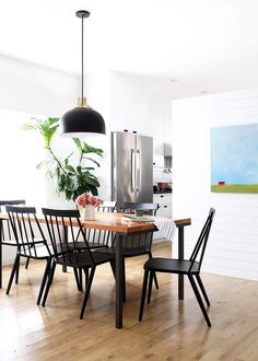 a dining room table with four chairs and a plant in the center, on top of a hard wood floor