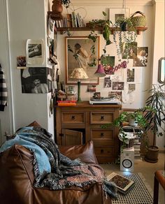 a living room filled with lots of plants and pictures on the wall next to a brown leather couch