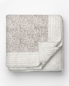a white quilted blanket on top of a bed