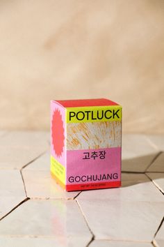 a pink and yellow box sitting on top of a white tile floor with the word potluck written in chinese