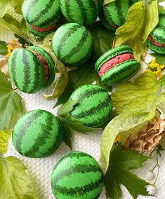 green macaroons with red stripes on them are surrounded by leaves and yellow flowers