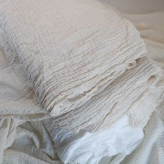 an unmade bed with white linens and sheets on top of eachother