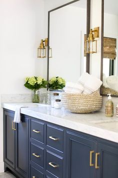 an image of a bathroom with blue cabinets and white marble counter tops on the phone