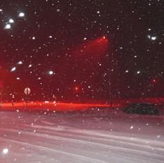 snow falling on the ground at night with street lights