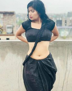 a woman in black sari posing for the camera with her hands on her hips