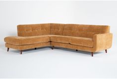 a brown sectional couch sitting on top of a white floor next to a wooden frame