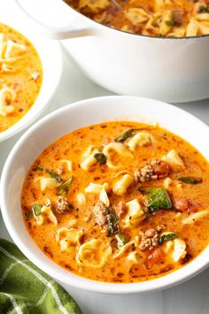 two bowls filled with pasta soup on top of a table