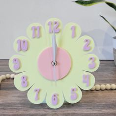 a clock that has numbers on it and is sitting next to a potted plant