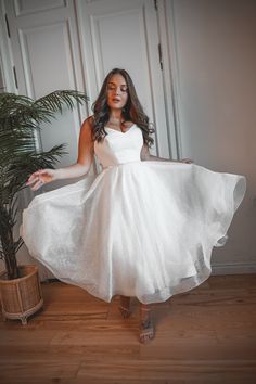 a woman in a white dress is posing for the camera