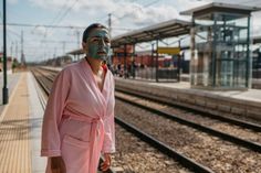 a man in a bathrobe is standing on the train tracks with his face painted