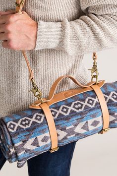 a woman is holding a blue and white patterned duffel bag with gold hardwares