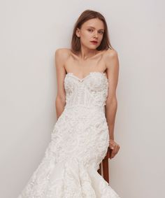 a woman in a wedding dress leaning on a chair