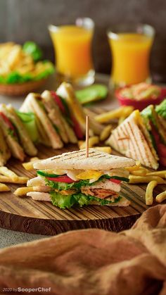 a wooden cutting board topped with a cut in half sandwich and french fries