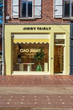 a yellow store front with a plant in the window