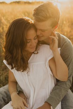 a man and woman cuddle together in a field