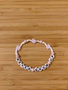 a pink and white beaded bracelet that says never grow