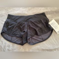 a pair of black shorts sitting on top of a white bed next to a tag