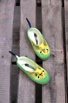 two green slippers with yellow and black designs on them sitting on wooden planks