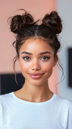 a young woman with her hair in a messy topknot is smiling at the camera