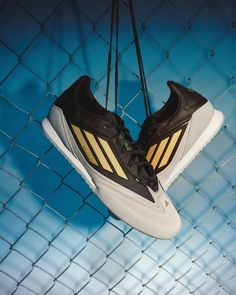 a pair of shoes hanging on a chain link fence in front of a blue background