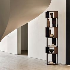 a tall book shelf sitting on top of a hard wood floor next to a white wall