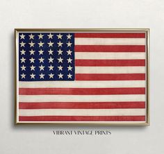 an american flag hanging on the wall in front of a white wall with a gold frame