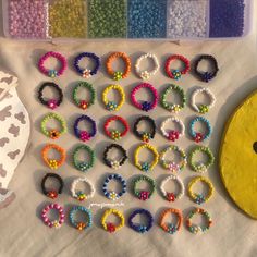 there are many bracelets on the table next to some beads and a paper plate