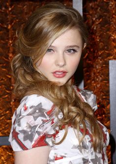 a young woman with long hair wearing a floral dress and red lipstick is posing for the camera