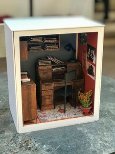 a miniature model of a desk and chair in a room with a potted plant