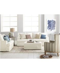 a living room with white furniture and blue accents