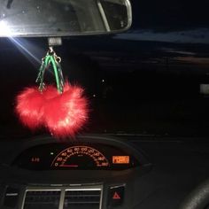 a car dashboard with a fuzzy red object hanging from it's dash board in the dark