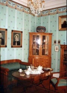 an old fashioned dining room with blue wallpaper and wooden furniture, including a china cabinet