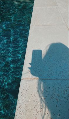 the shadow of a person standing next to a swimming pool