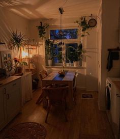 a dining room table and chairs in front of a window with potted plants on it