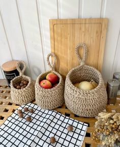 three baskets filled with apples sitting on top of a wooden table next to other items