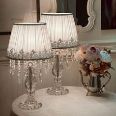 two lamps sitting on top of a table next to a vase with flowers in it