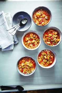 six bowls of soup on a table with spoons and napkins next to them