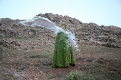 a woman standing on top of a grass covered hillside