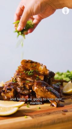 someone is sprinkling parsley on some meat with lemons and broccoli