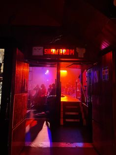 people are standing in the doorway of a building with red light coming from behind it