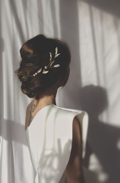 a woman wearing a white dress standing in front of a curtain with her back to the camera